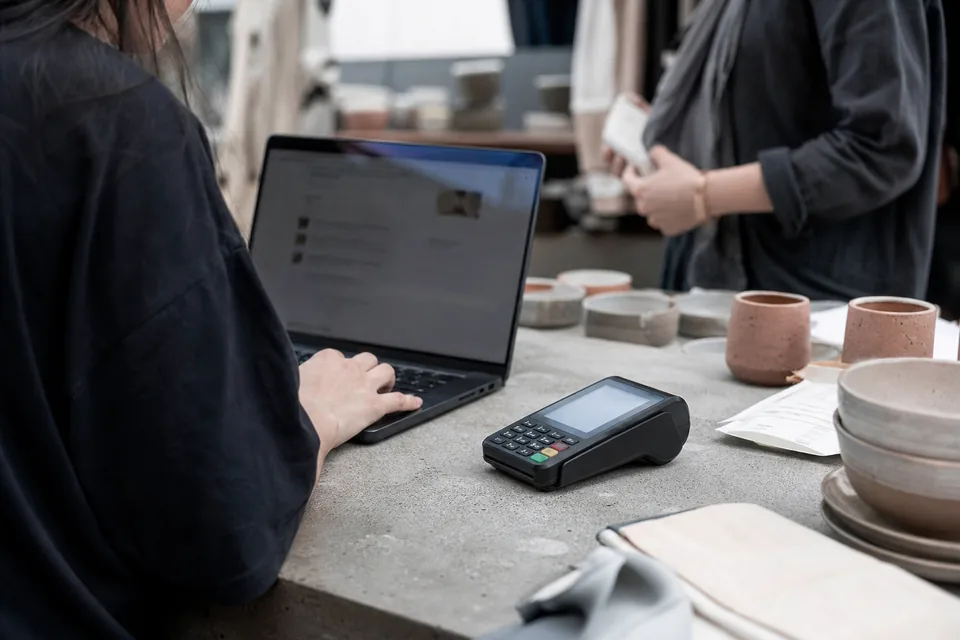 Card payment terminal and laptop checkout on a shop counter