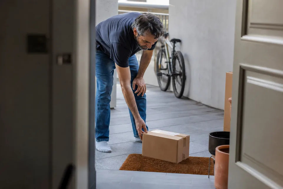 Customer picking up a delivered parcel at his front door