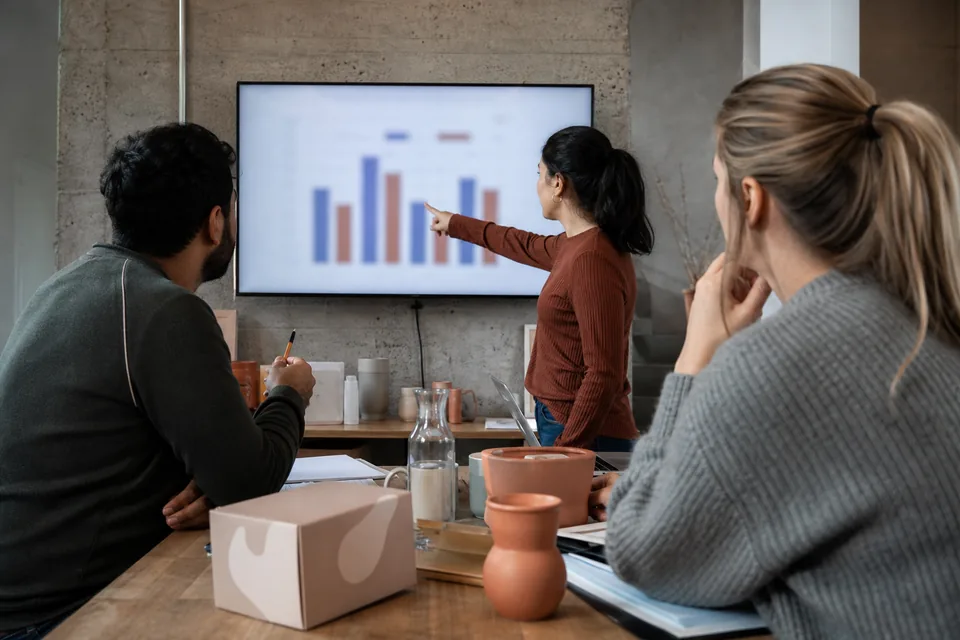 Small ecommerce team reviewing revenue charts on a large monitor